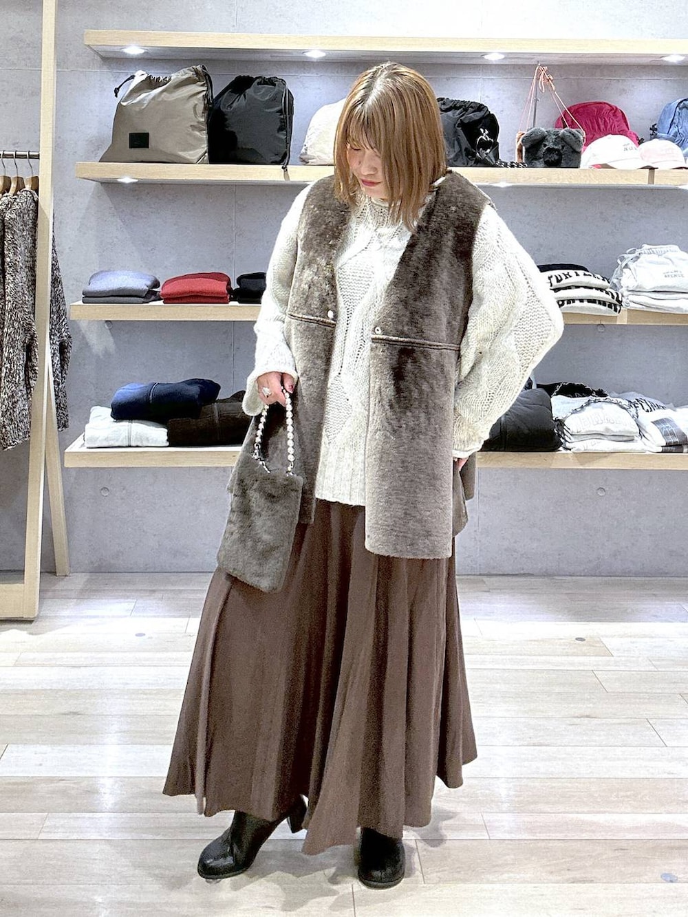 グレー系のニット/セーター、ブラック系のブーツ、グレー系のショルダーバッグを着用したレディースの冬コーディネートの3枚目の写真