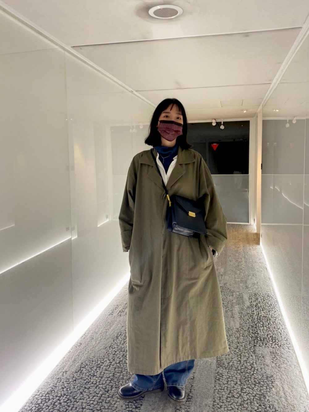 ホワイト系のシャツワンピース、ブラック系のその他シューズ、グリーン系のチェスターコートを着用したレディースの冬コーディネートの2枚目の写真