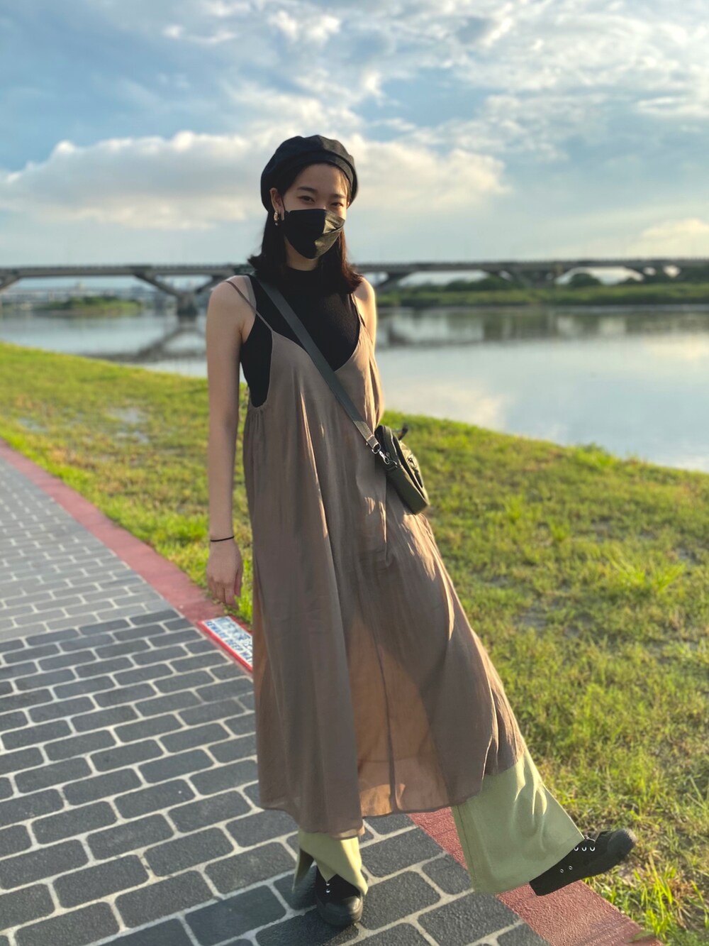 ベージュ系のジャンパースカート、グリーン系のスラックス、ブラック系のシューズを着用したレディースの夏コーディネートの2枚目の写真