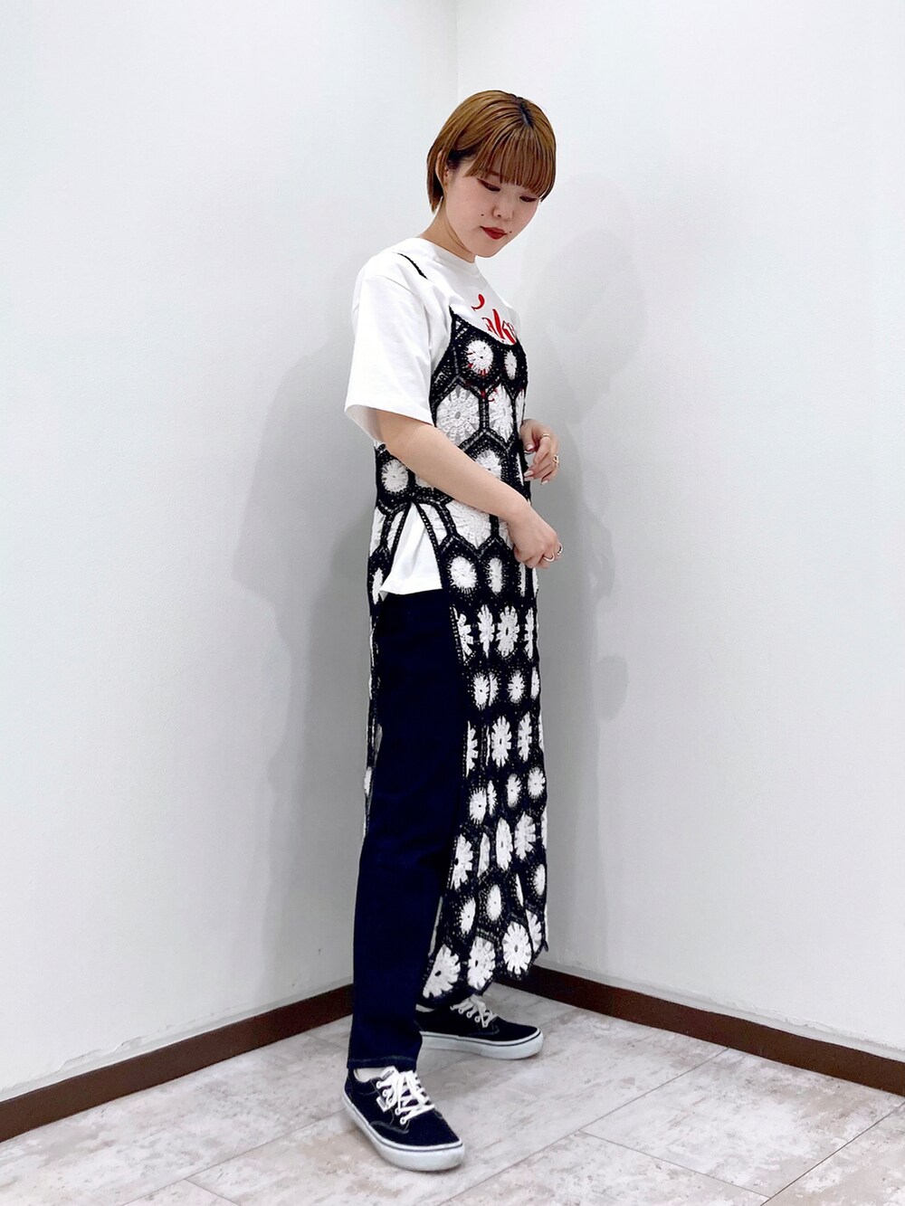 ブラック系のワンピース、ホワイト系のTシャツ/カットソー、ブルー系のデニムパンツを着用したレディースの春コーディネートの2枚目の写真