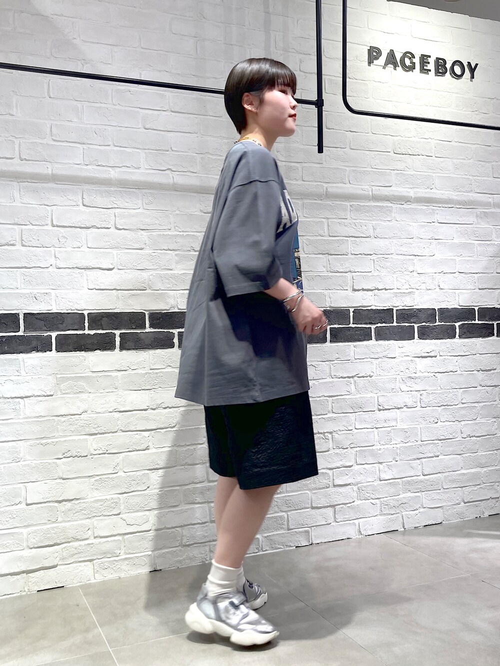 グレー系のTシャツ/カットソー、ブラック系のその他パンツ、シルバー系のスニーカーを着用したレディースの春コーディネートの3枚目の写真