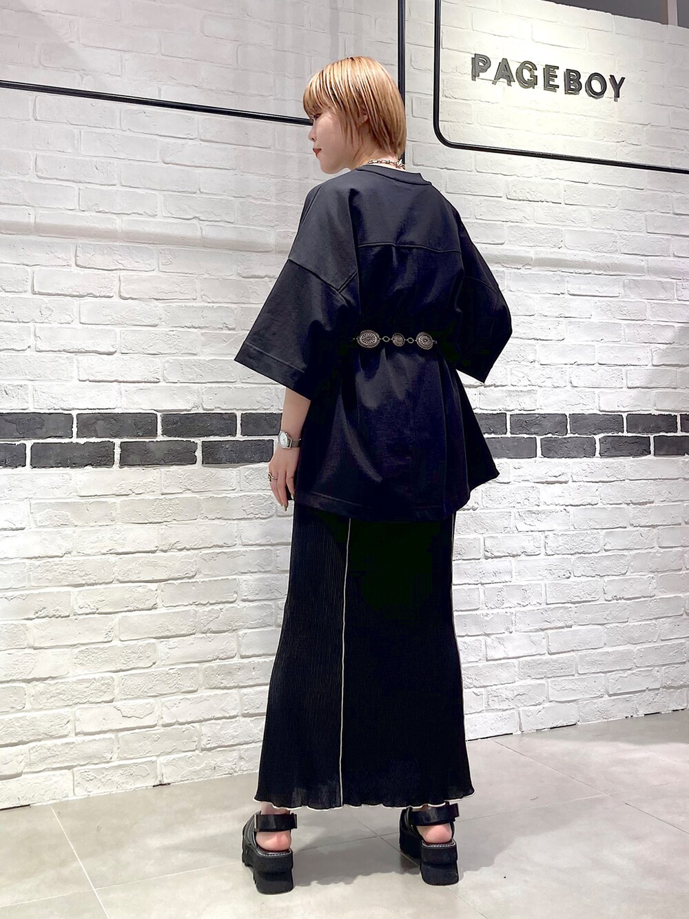 ブラック系のTシャツ/カットソー、ブラック系のスカート、ブラック系のサンダルを着用したレディースの春コーディネートの5枚目の写真