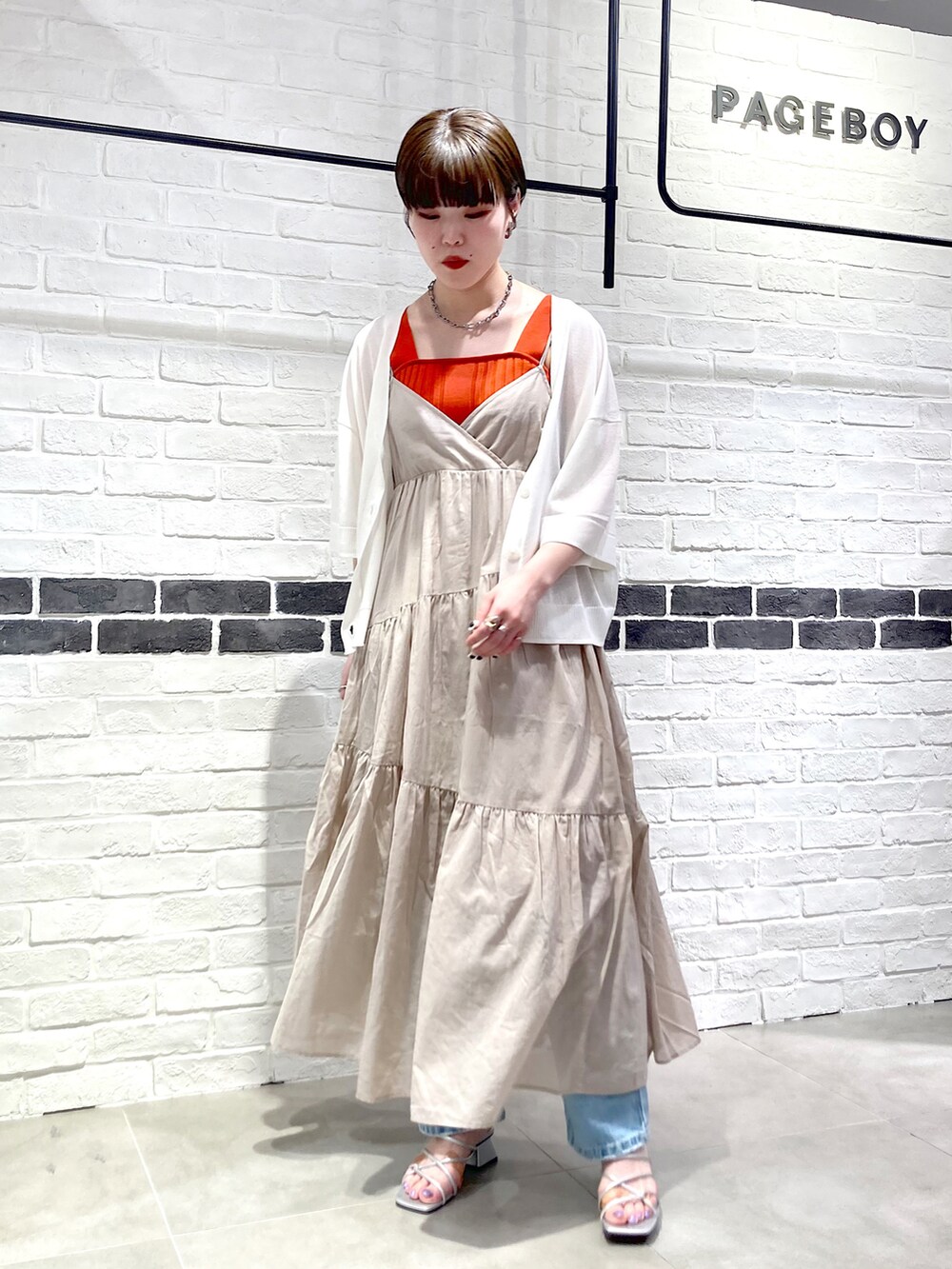 ベージュ系のワンピース、ホワイト系のカーディガン/ボレロ、オレンジ系のタンクトップを着用したレディースの夏コーディネートの2枚目の写真