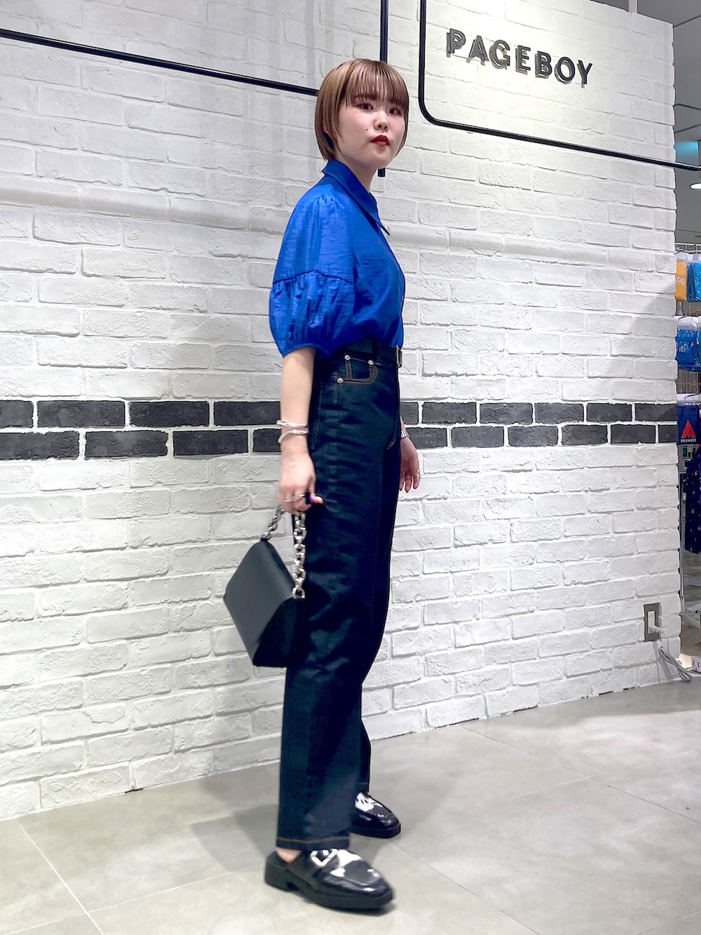 ブルー系のシャツ/ブラウス、ブラック系のショルダーバッグ、その他のローファーを着用したレディースの春コーディネートの2枚目の写真