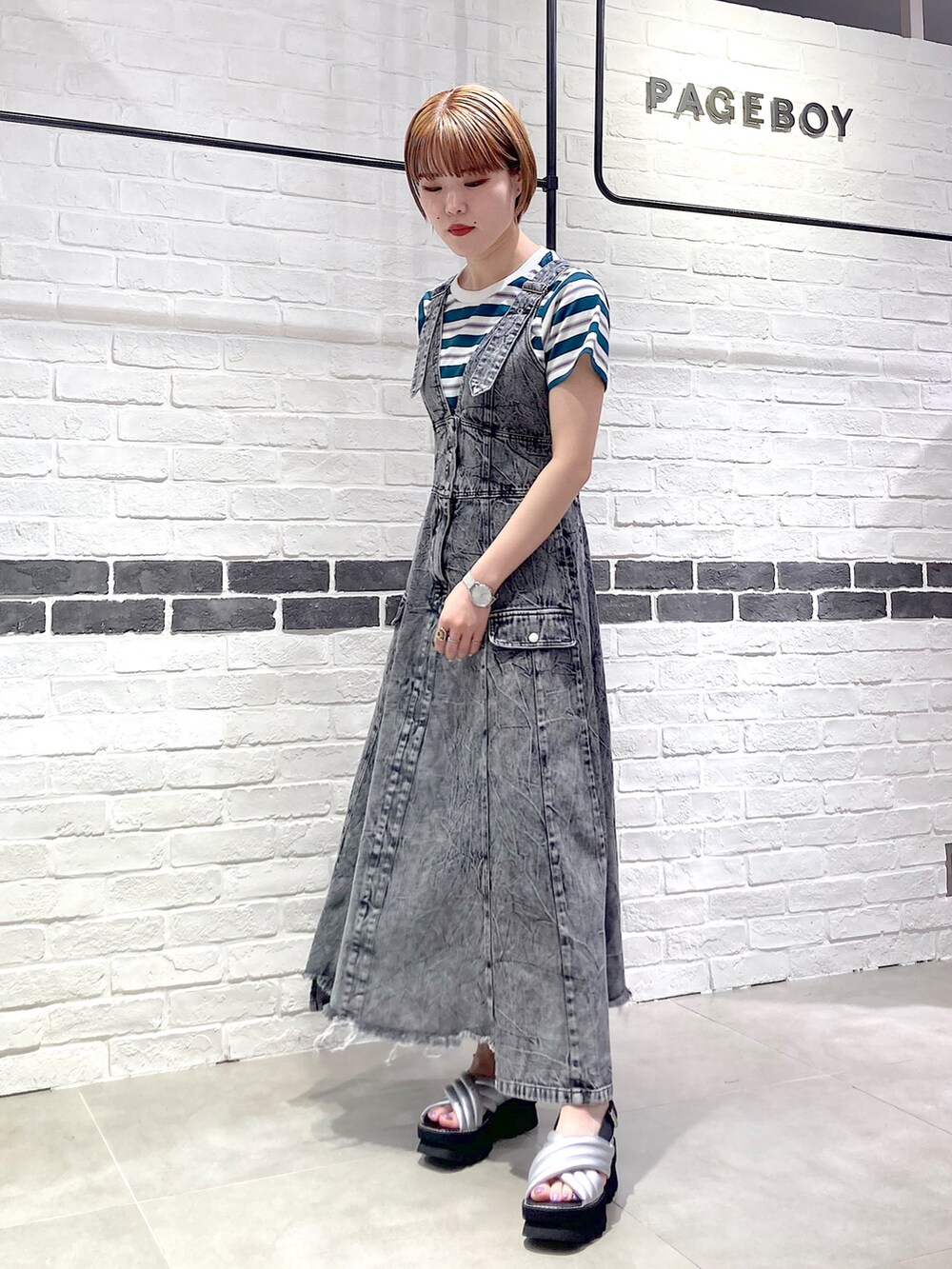 ブラック系のワンピース、グリーン系のTシャツ/カットソー、シルバー系のサンダルを着用したレディースの春コーディネートの2枚目の写真