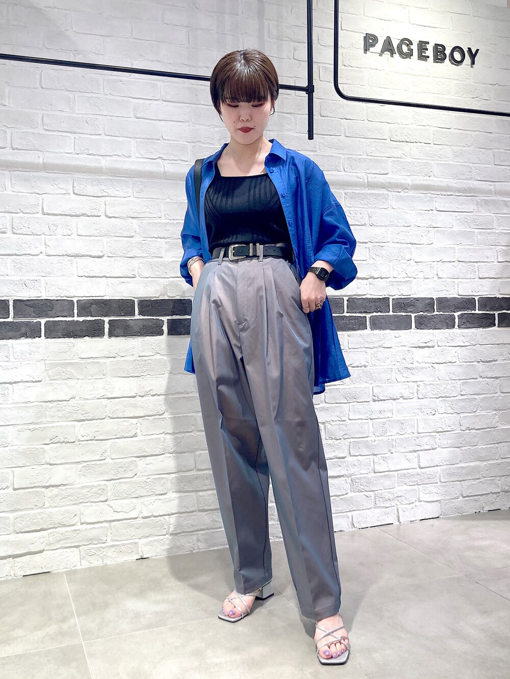 ブラック系のタンクトップ、ブルー系のシャツ/ブラウス、グレー系のスラックスを着用したレディースの夏コーディネートの2枚目の写真