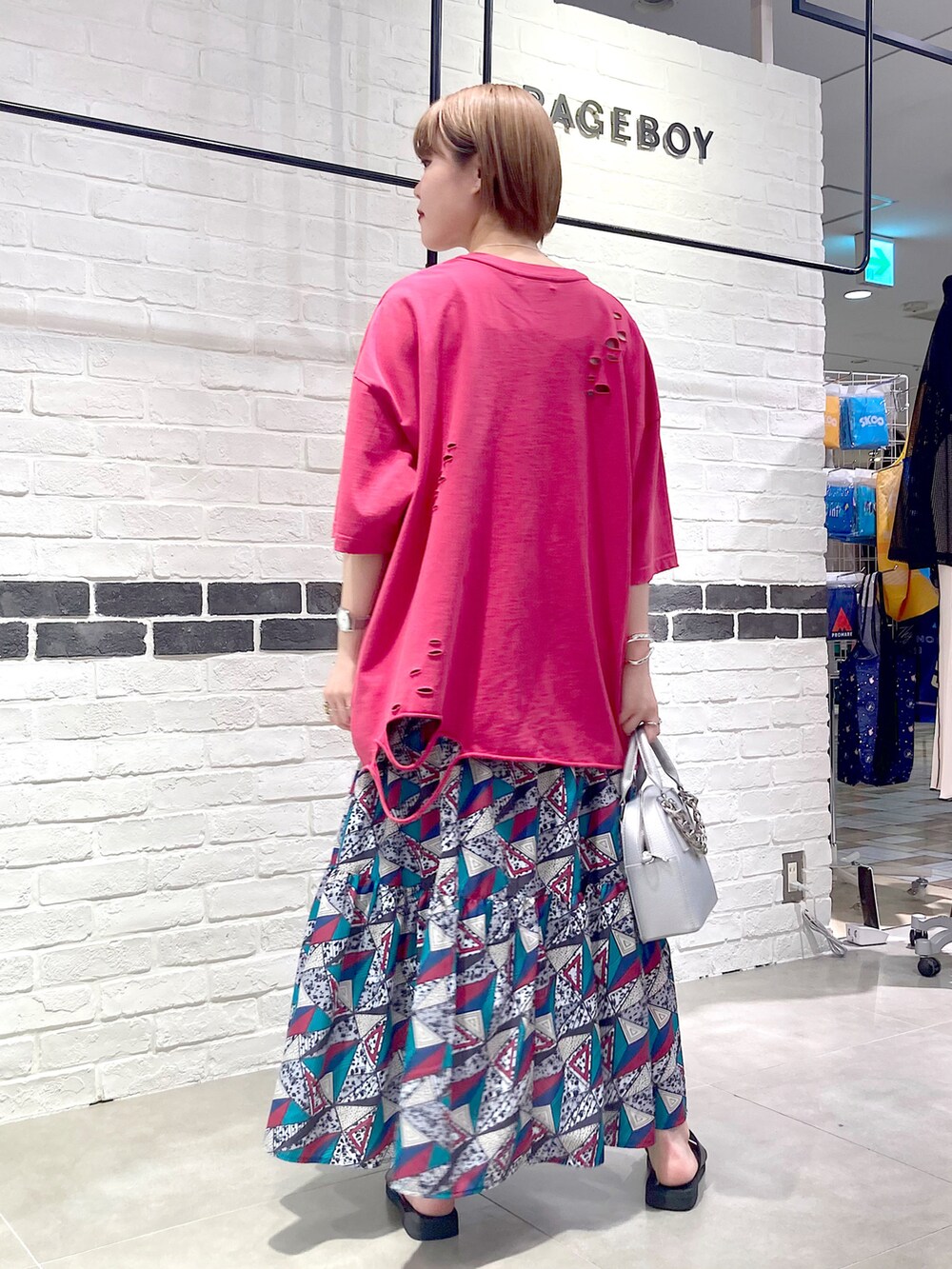 シルバー系のショルダーバッグ、ピンク系のTシャツ/カットソー、ホワイト系のスカートを着用したレディースの春コーディネートの4枚目の写真