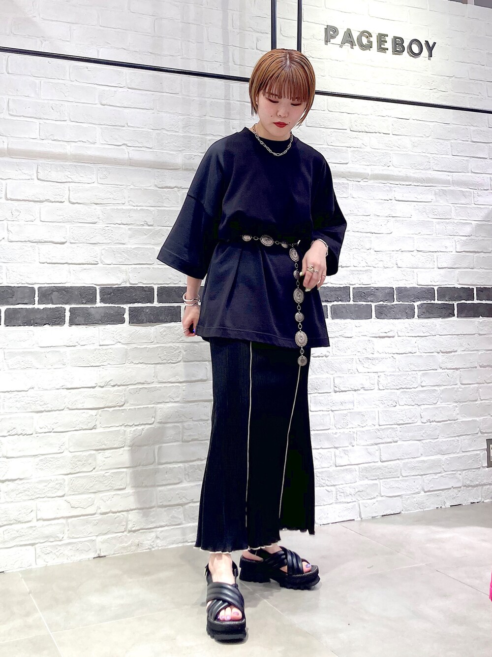 ブラック系のTシャツ/カットソー、ブラック系のスカート、ブラック系のサンダルを着用したレディースの春コーディネートの2枚目の写真