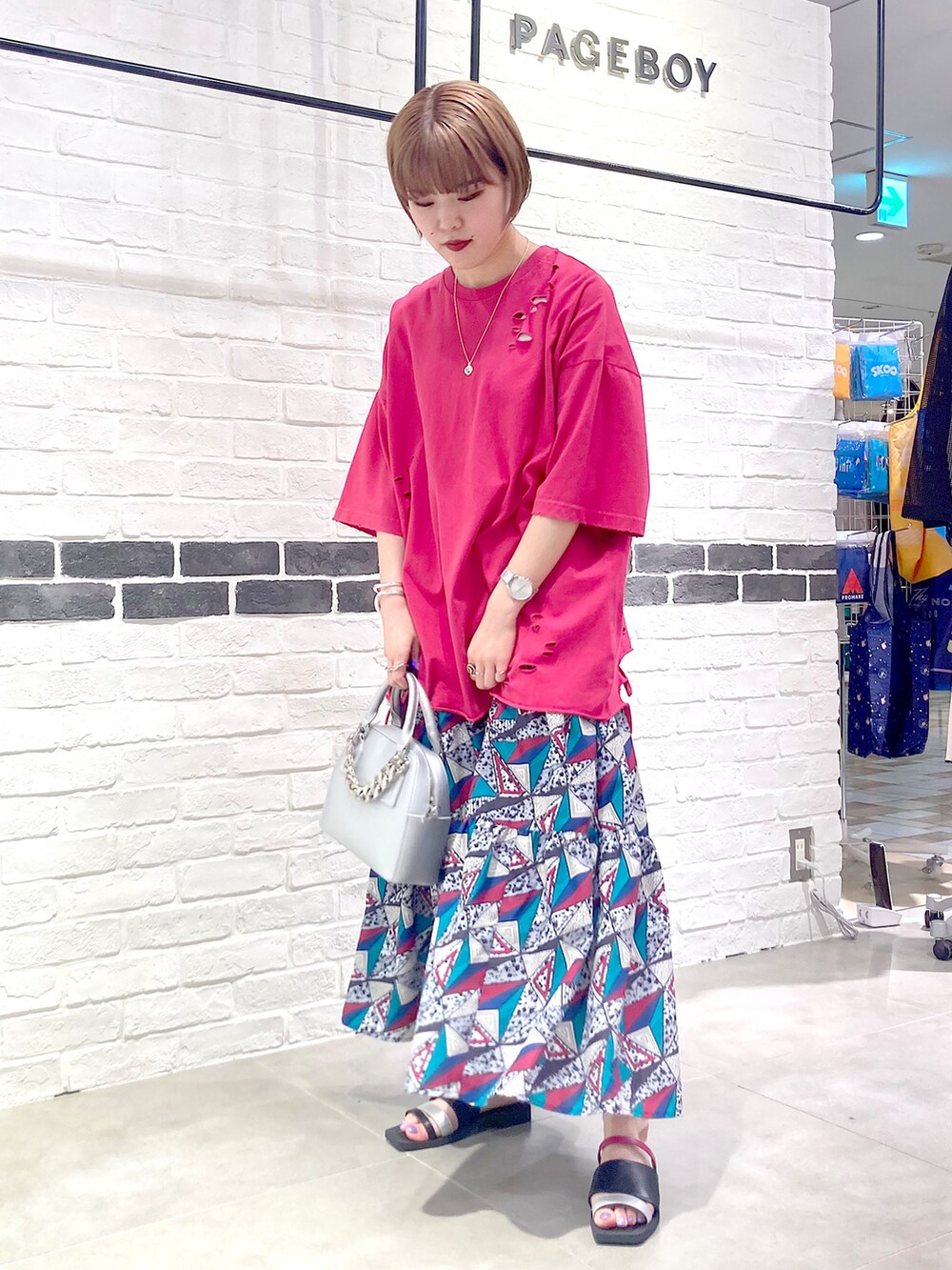 シルバー系のショルダーバッグ、ピンク系のTシャツ/カットソー、ホワイト系のスカートを着用したレディースの春コーディネートの3枚目の写真