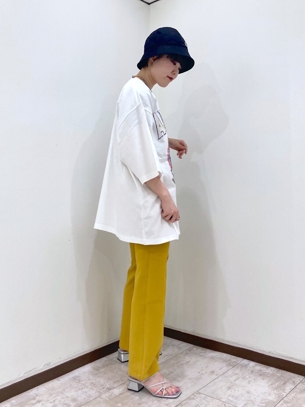 ホワイト系のTシャツ/カットソー、イエロー系のスラックス、シルバー系のサンダルを着用したレディースの夏コーディネートの3枚目の写真