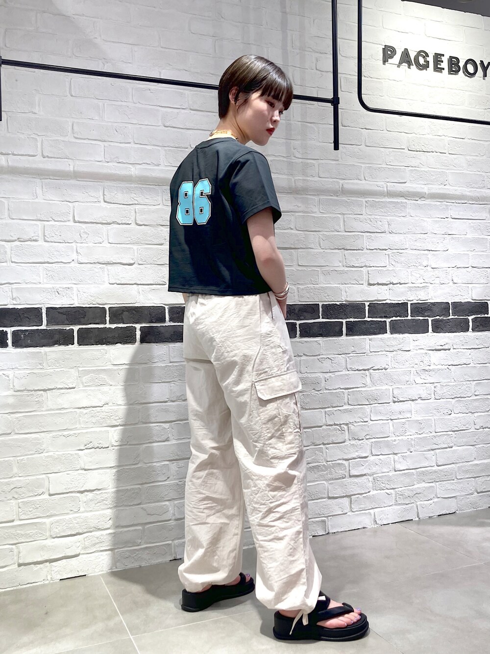 ブラック系のTシャツ/カットソー、ブラック系のショルダーバッグ、ホワイト系のカーゴパンツを着用したレディースの春コーディネートの3枚目の写真