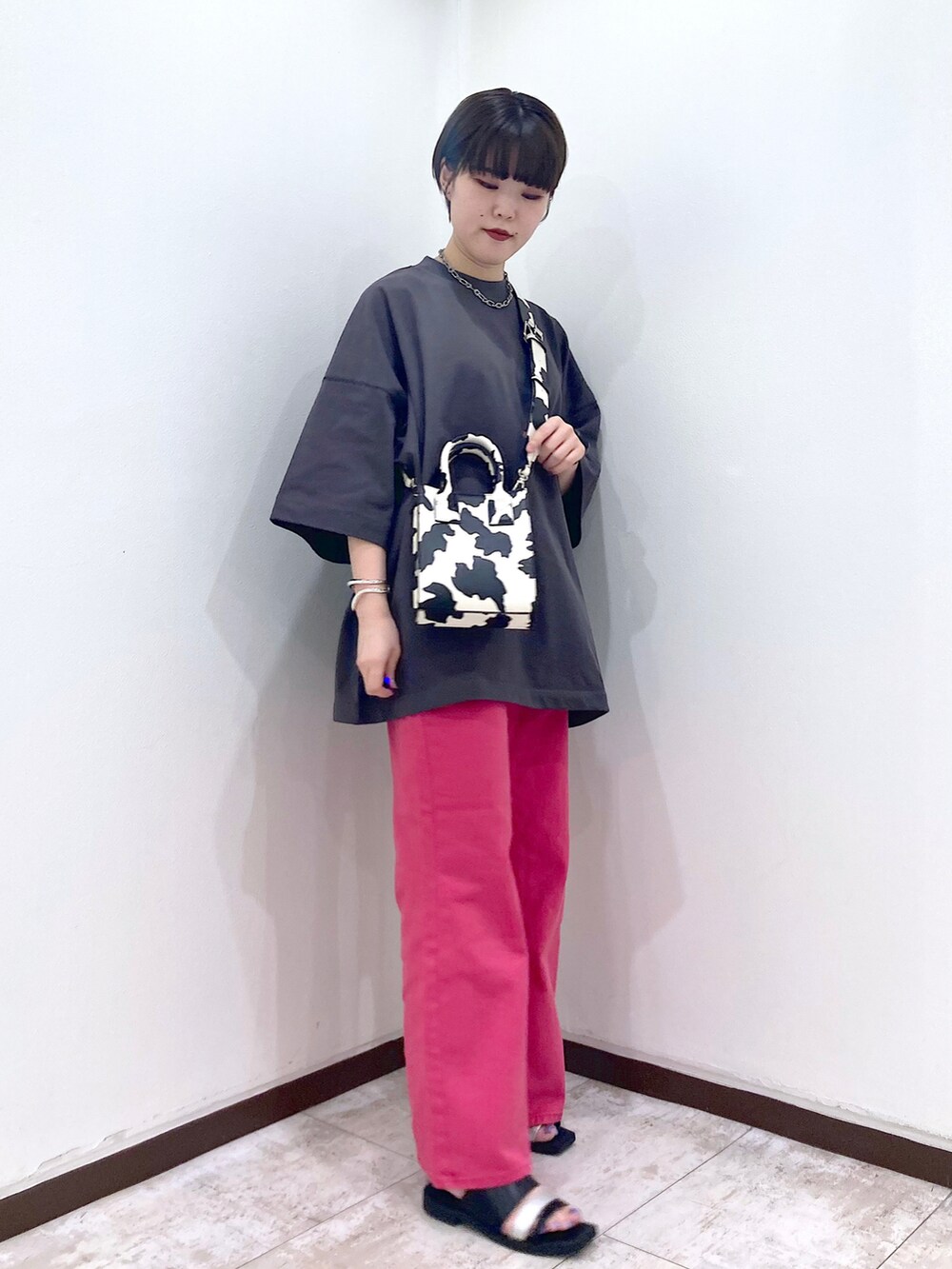 ピンク系のデニムパンツ、グレー系のTシャツ/カットソー、ホワイト系のショルダーバッグを着用したレディースの夏コーディネートの2枚目の写真