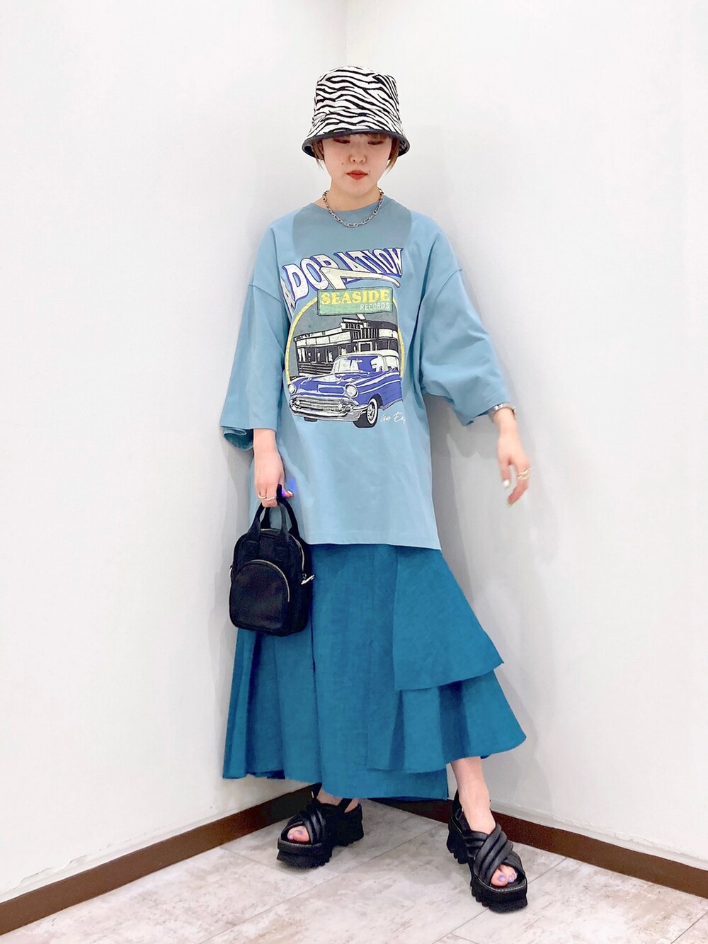 ブルー系のTシャツ/カットソー、ブラック系のショルダーバッグ、ブルー系のスカートを着用したレディースの春コーディネートの3枚目の写真