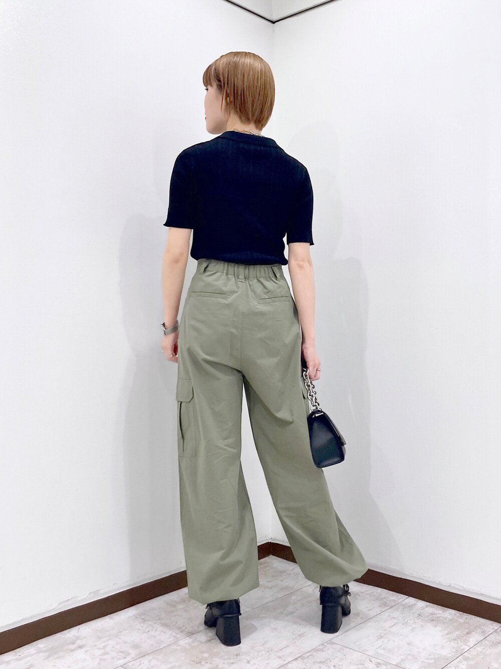 ブラック系のニット/セーター、ピンク系のタンクトップ、ブラック系のショルダーバッグを着用したレディースの春コーディネートの5枚目の写真