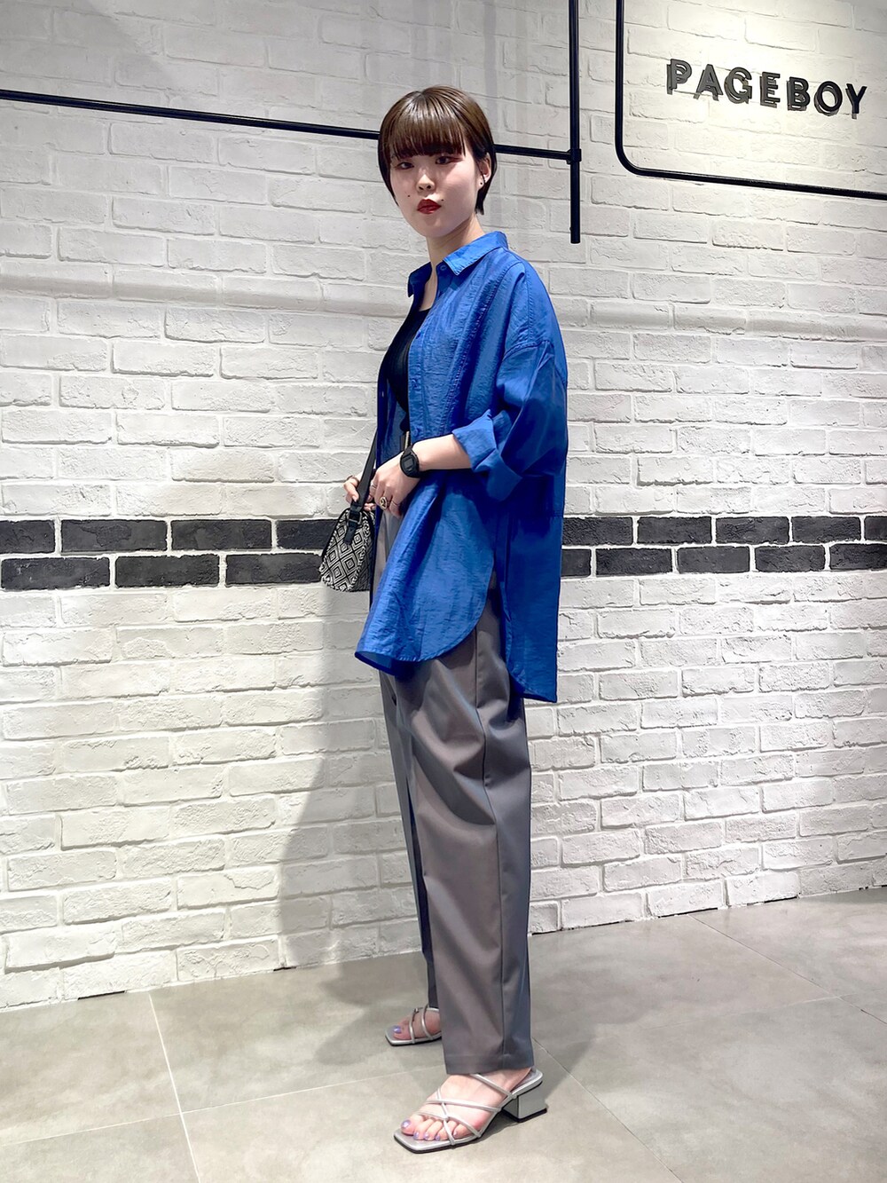 ブラック系のタンクトップ、ブルー系のシャツ/ブラウス、グレー系のスラックスを着用したレディースの夏コーディネートの3枚目の写真