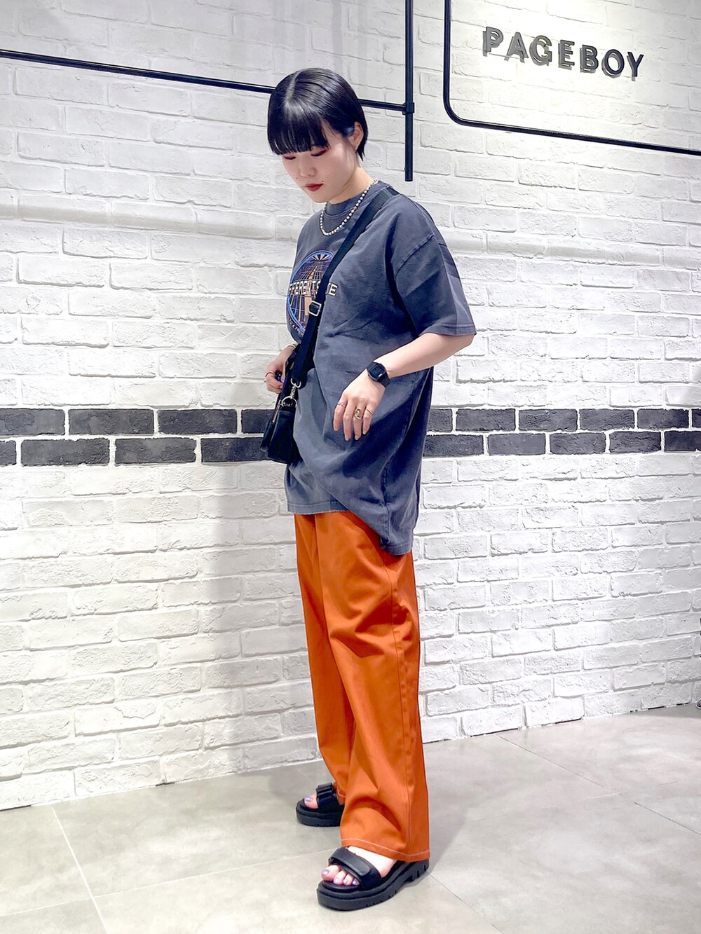 オレンジ系のその他パンツ、ブラック系のサンダル、グレー系のTシャツ/カットソーを着用したレディースの夏コーディネートの3枚目の写真