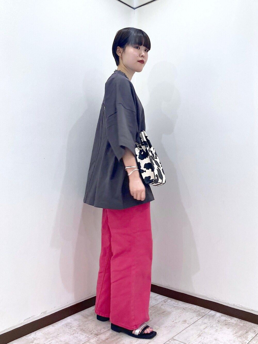 ピンク系のデニムパンツ、グレー系のTシャツ/カットソー、ホワイト系のショルダーバッグを着用したレディースの夏コーディネートの4枚目の写真