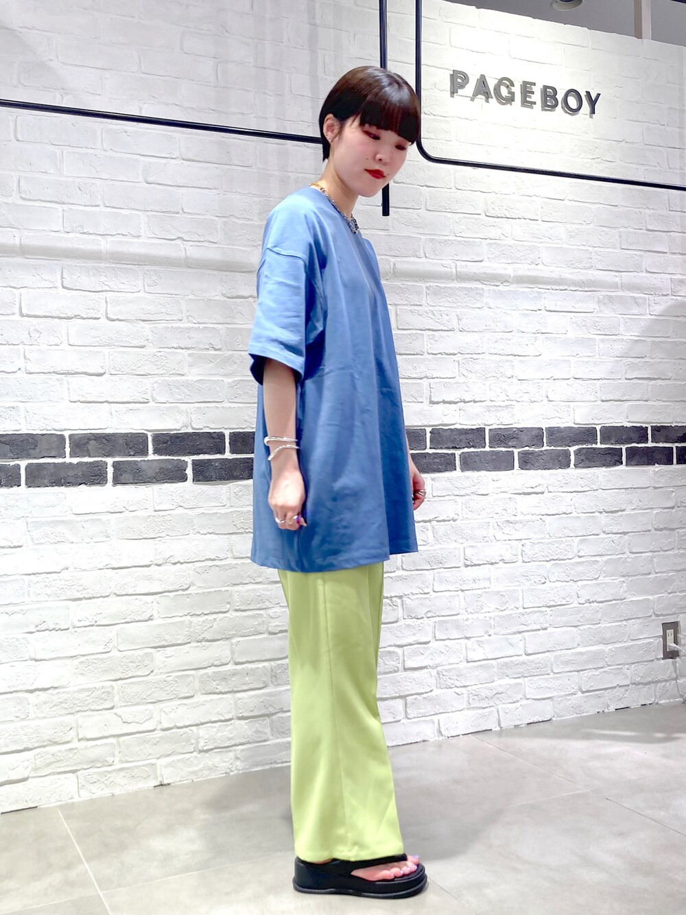 グリーン系のスラックス、ブルー系のTシャツ/カットソー、ブラック系のサンダルを着用したレディースの春コーディネートの4枚目の写真