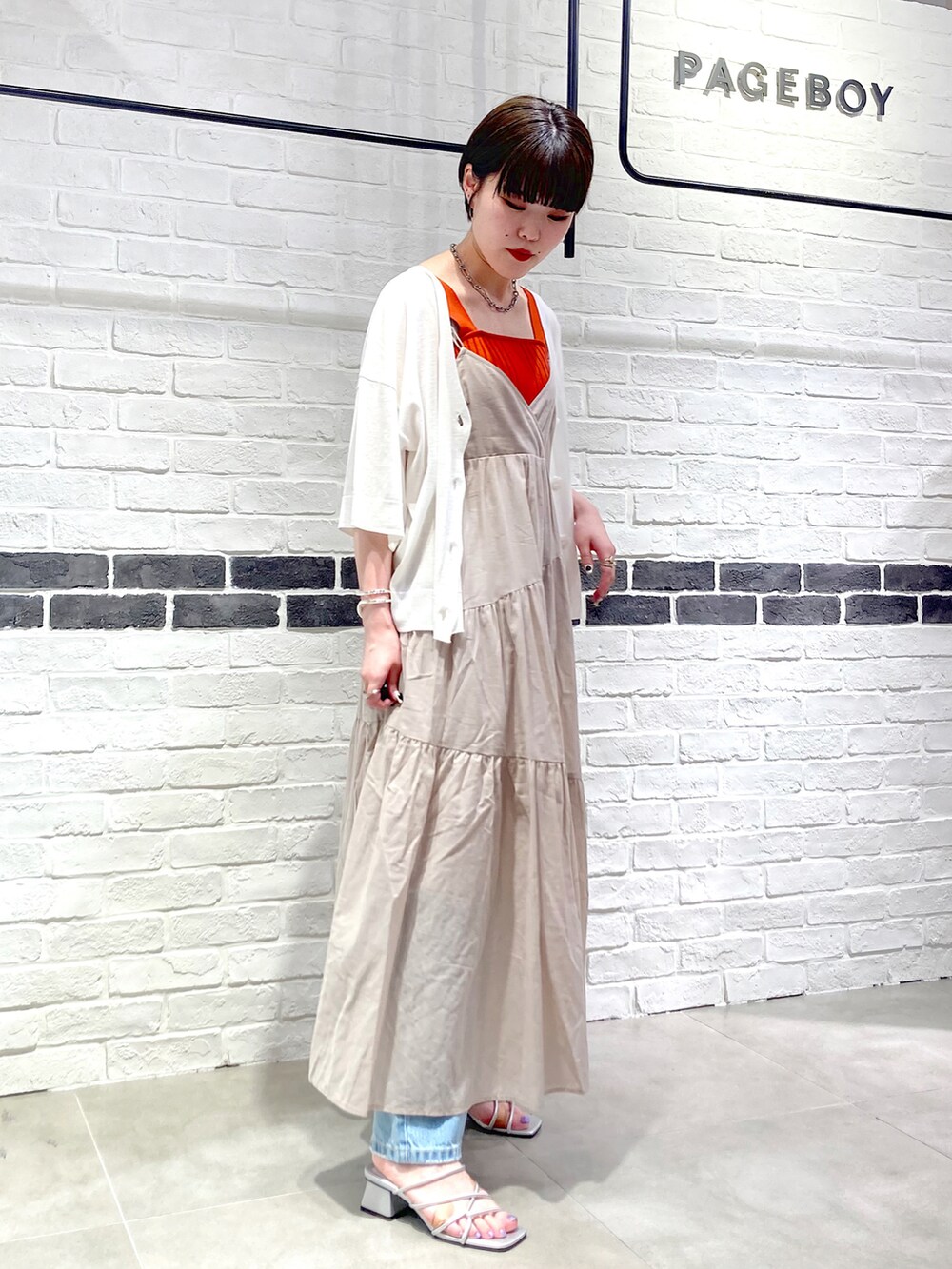 ベージュ系のワンピース、ホワイト系のカーディガン/ボレロ、オレンジ系のタンクトップを着用したレディースの夏コーディネートの3枚目の写真