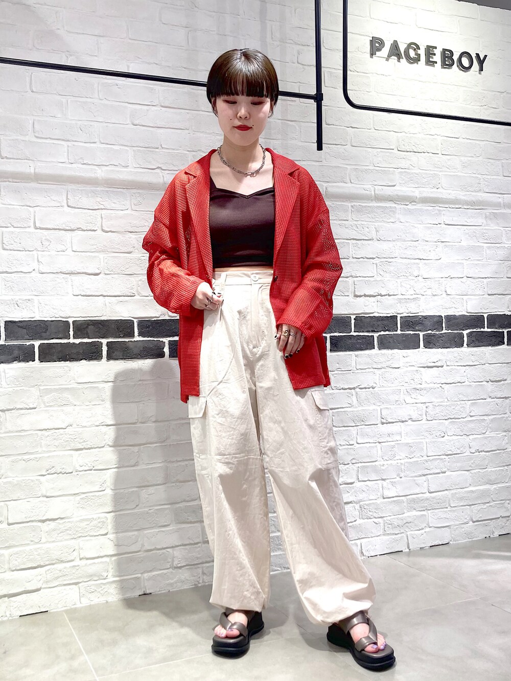 オレンジ系のテーラードジャケット、ブラウン系のタンクトップ、ホワイト系のカーゴパンツを着用したレディースの春コーディネートの2枚目の写真