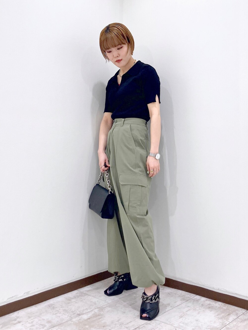 ブラック系のニット/セーター、ピンク系のタンクトップ、ブラック系のショルダーバッグを着用したレディースの春コーディネートの4枚目の写真