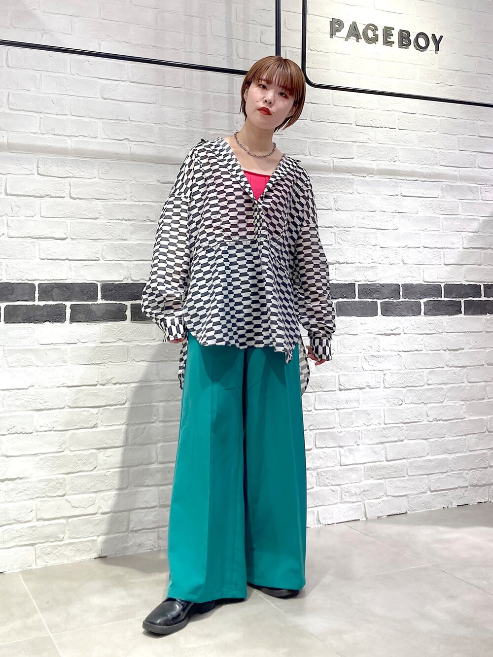 グリーン系のスラックス、ブラック系のシャツ/ブラウス、ピンク系のタンクトップを着用したレディースの春コーディネートの2枚目の写真