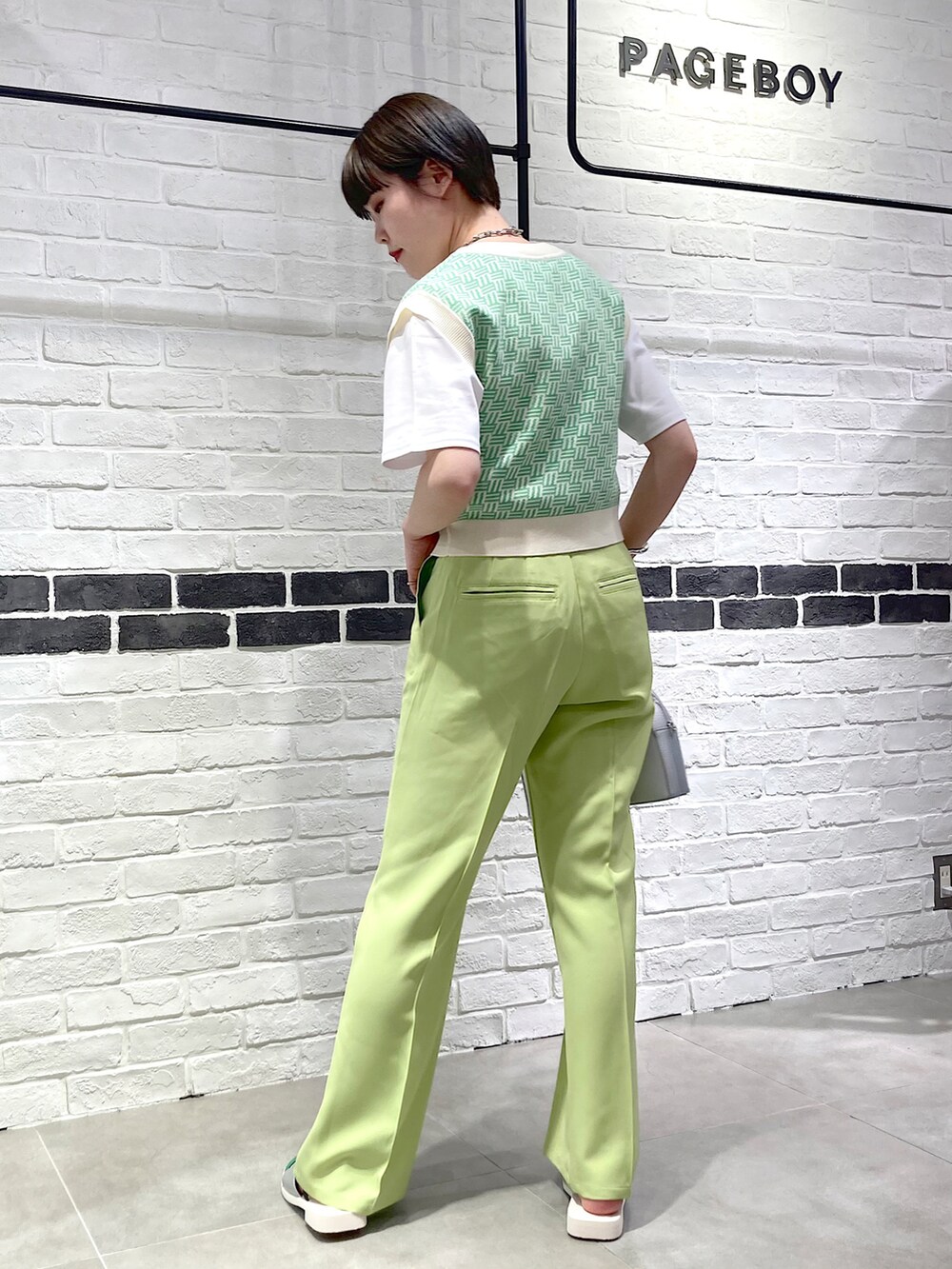 シルバー系のショルダーバッグ、グリーン系のスラックス、シルバー系のサンダルを着用したレディースの春コーディネートの4枚目の写真