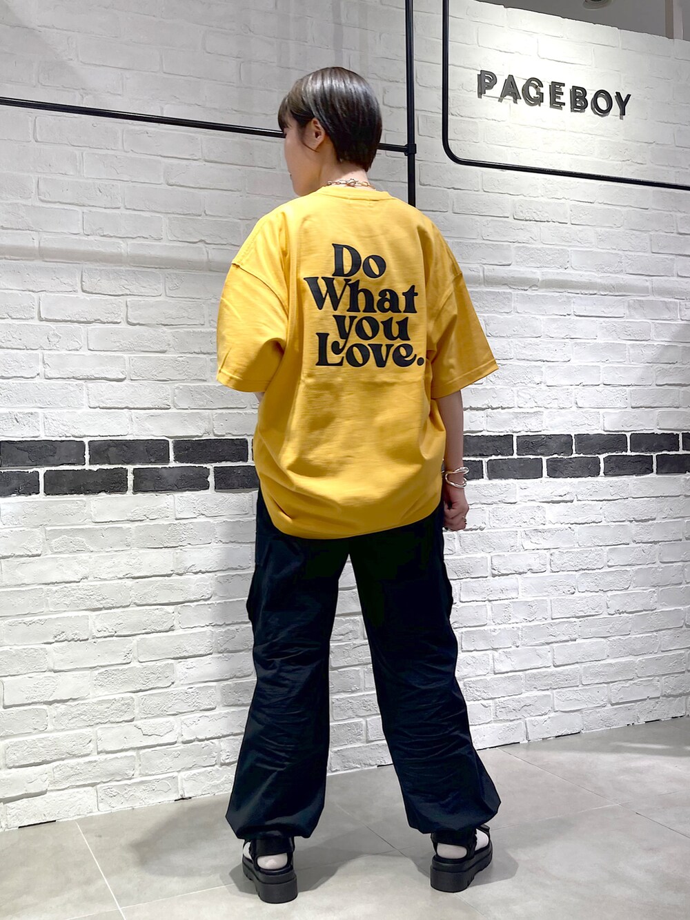 イエロー系のTシャツ/カットソー、ブラック系のカーゴパンツ、ブラック系のサンダルを着用したレディースの春コーディネートの3枚目の写真
