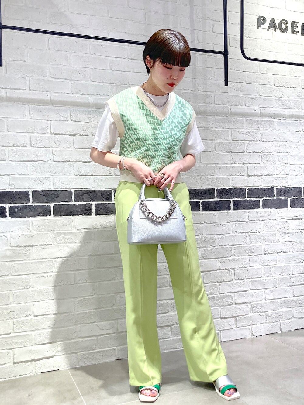 シルバー系のショルダーバッグ、グリーン系のスラックス、シルバー系のサンダルを着用したレディースの春コーディネートの2枚目の写真