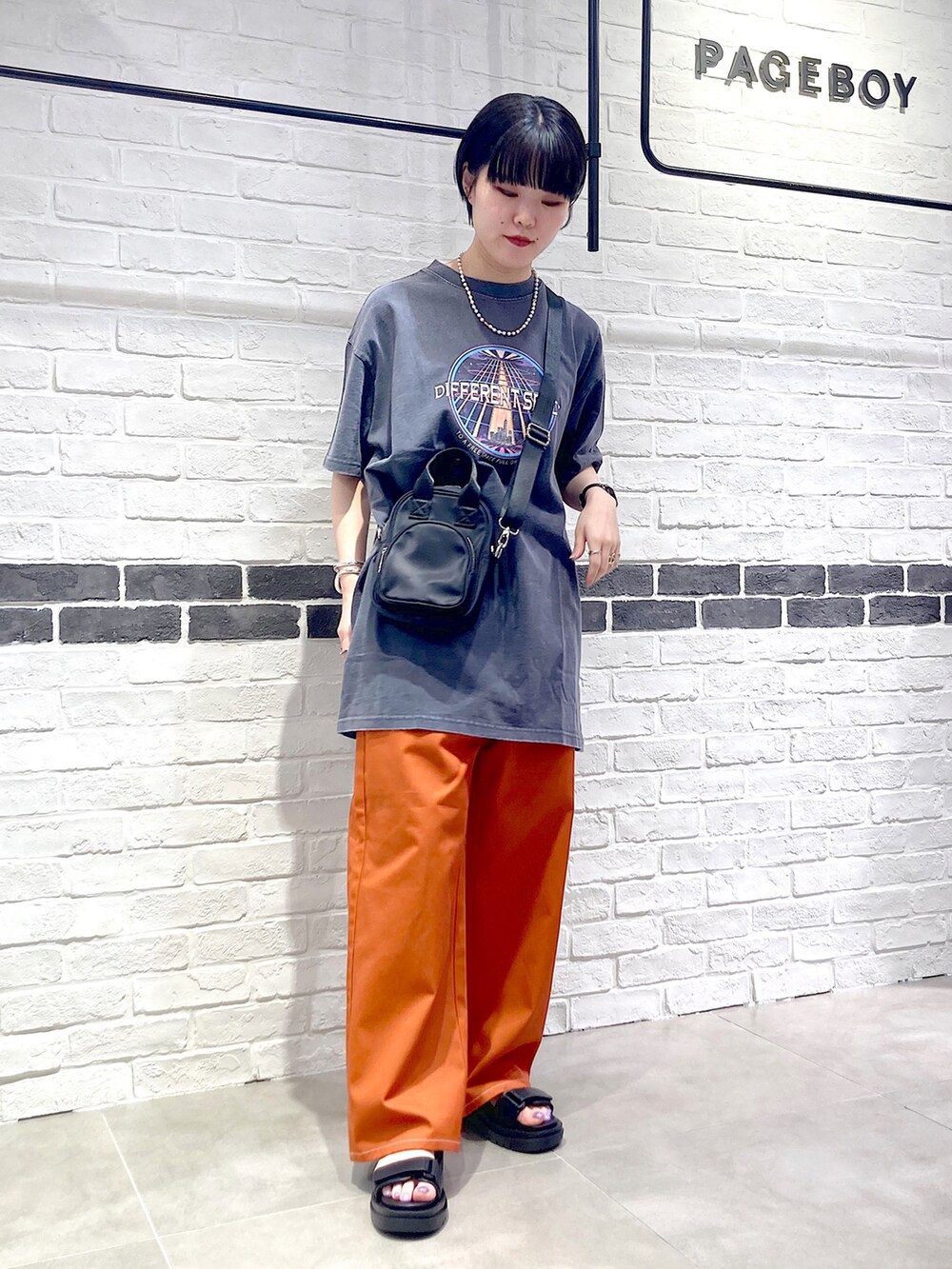 オレンジ系のその他パンツ、ブラック系のサンダル、グレー系のTシャツ/カットソーを着用したレディースの夏コーディネートの2枚目の写真