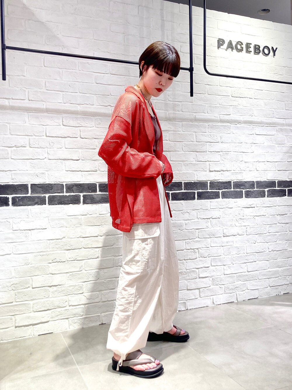 オレンジ系のテーラードジャケット、ブラウン系のタンクトップ、ホワイト系のカーゴパンツを着用したレディースの春コーディネートの3枚目の写真