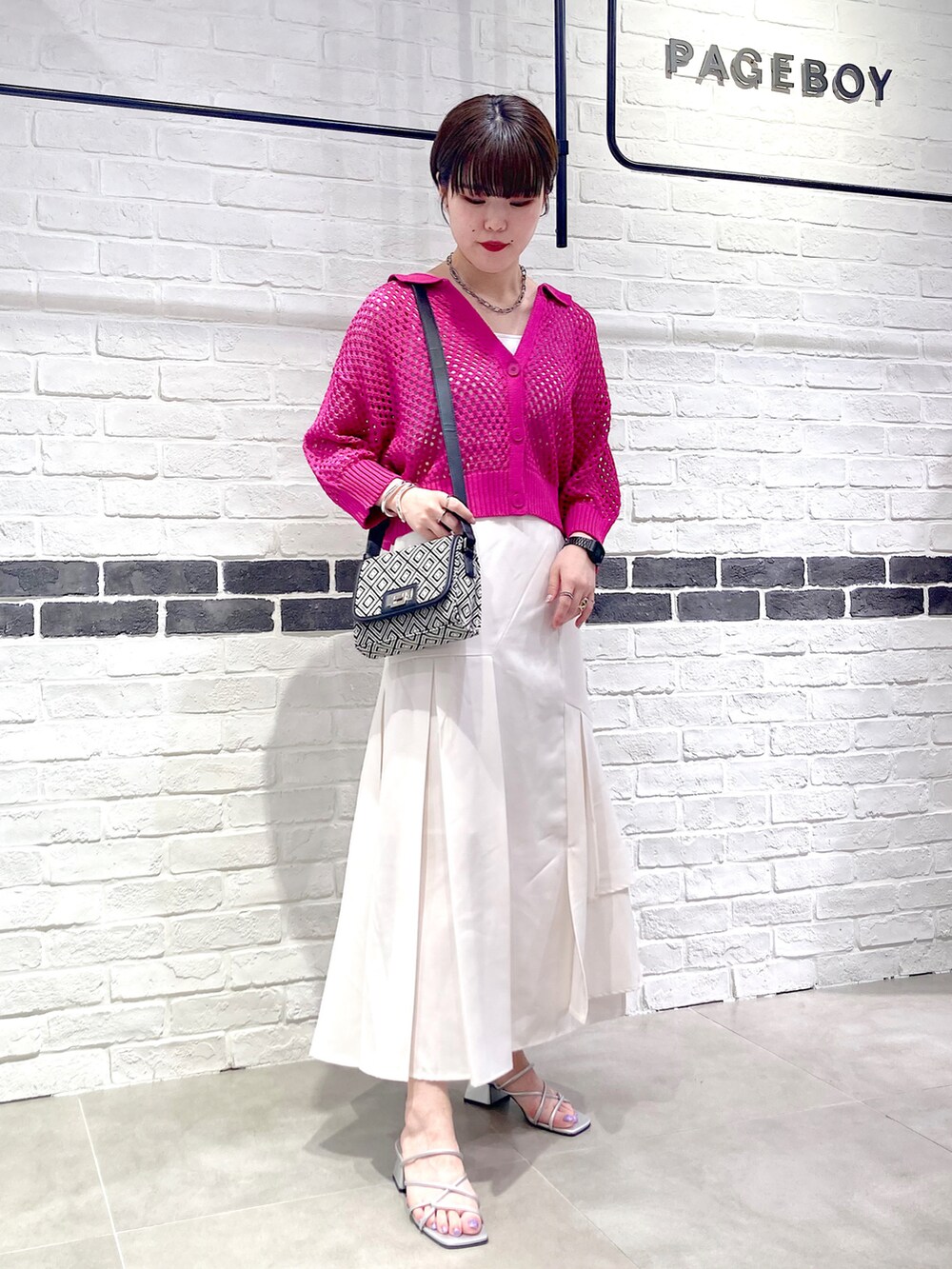 ピンク系のニット/セーター、ブラック系のショルダーバッグ、ホワイト系のタンクトップを着用したレディースの夏コーディネートの2枚目の写真