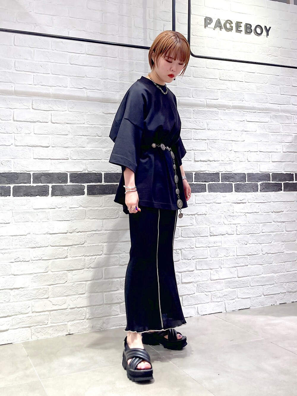 ブラック系のTシャツ/カットソー、ブラック系のスカート、ブラック系のサンダルを着用したレディースの春コーディネートの3枚目の写真