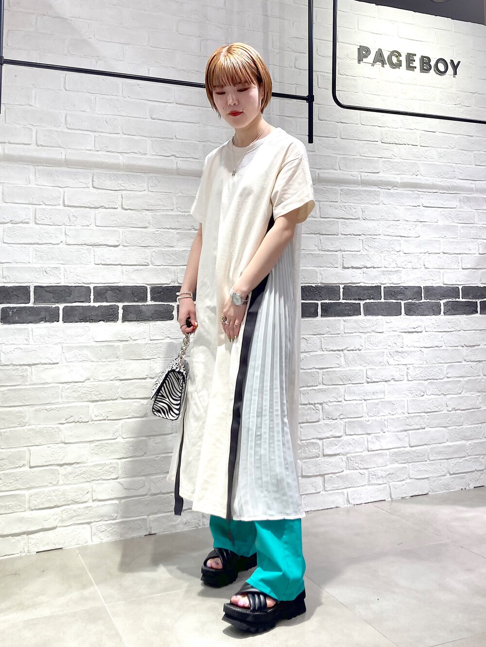 その他のショルダーバッグ、ホワイト系のワンピース、グリーン系のデニムパンツを着用したレディースの春コーディネートの2枚目の写真