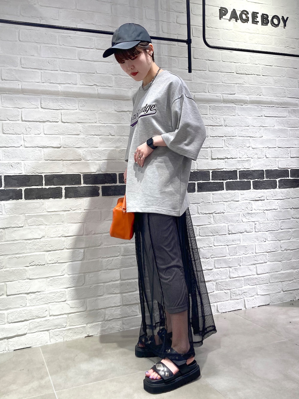 オレンジ系のショルダーバッグ、グレー系のTシャツ/カットソー、ブラック系のワンピースを着用したレディースの夏コーディネートの3枚目の写真