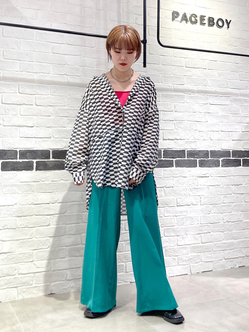 グリーン系のスラックス、ブラック系のシャツ/ブラウス、ピンク系のタンクトップを着用したレディースの春コーディネートの3枚目の写真