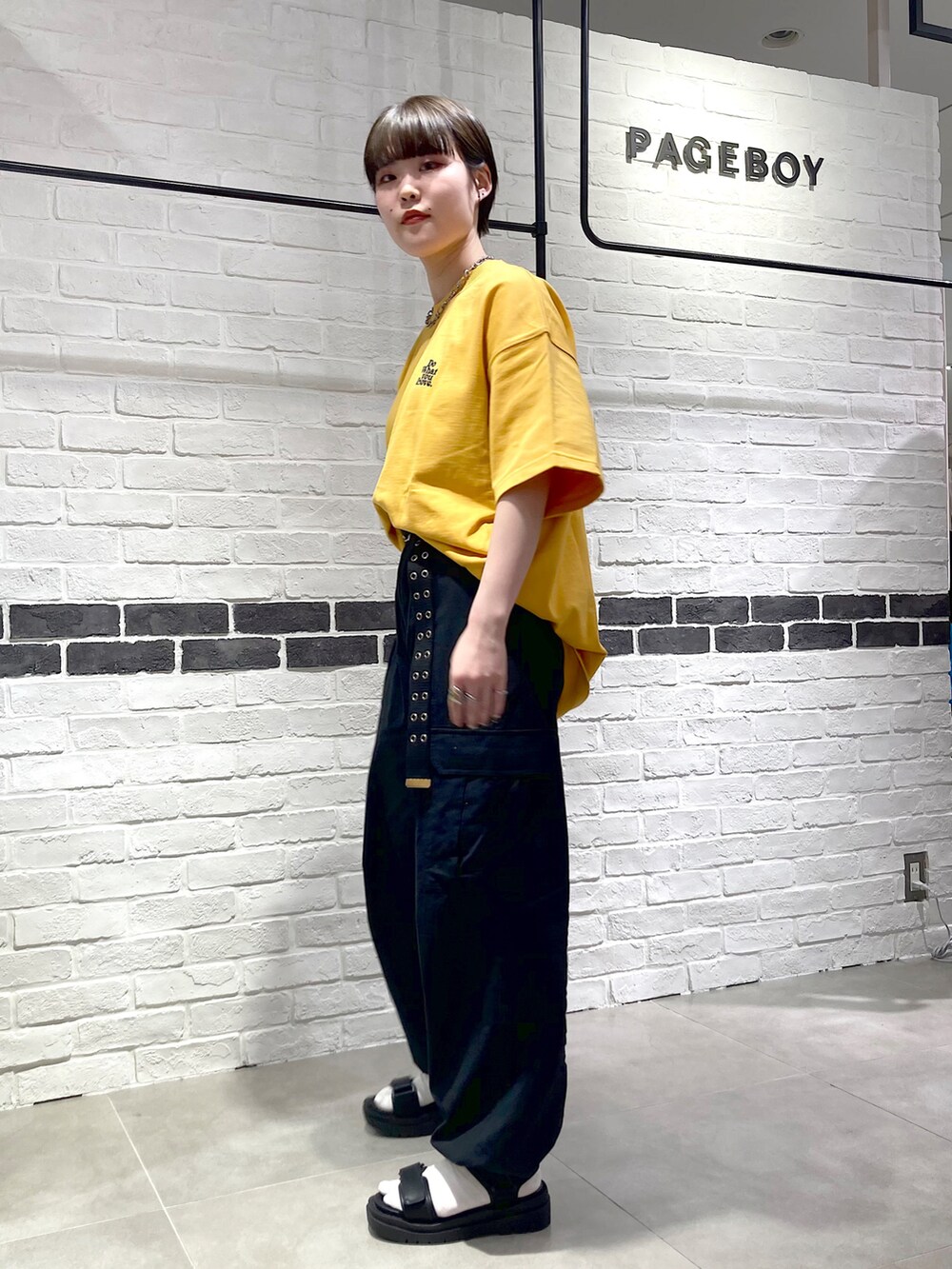 イエロー系のTシャツ/カットソー、ブラック系のカーゴパンツ、ブラック系のサンダルを着用したレディースの春コーディネートの2枚目の写真