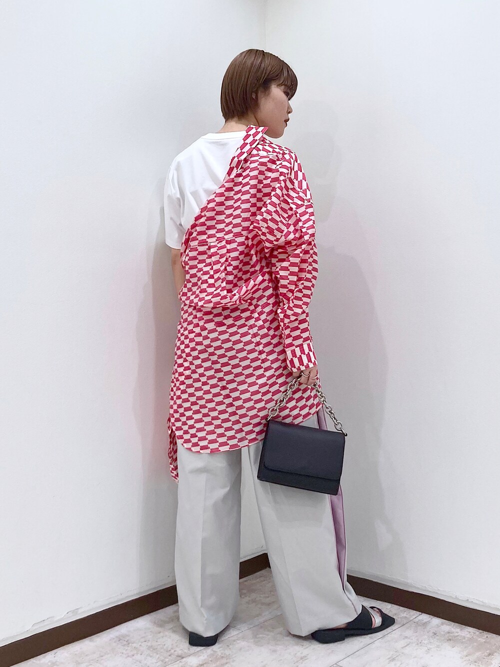 ブラック系のショルダーバッグ、ベージュ系のスラックス、オレンジ系のシャツ/ブラウスを着用したレディースの春コーディネートの4枚目の写真