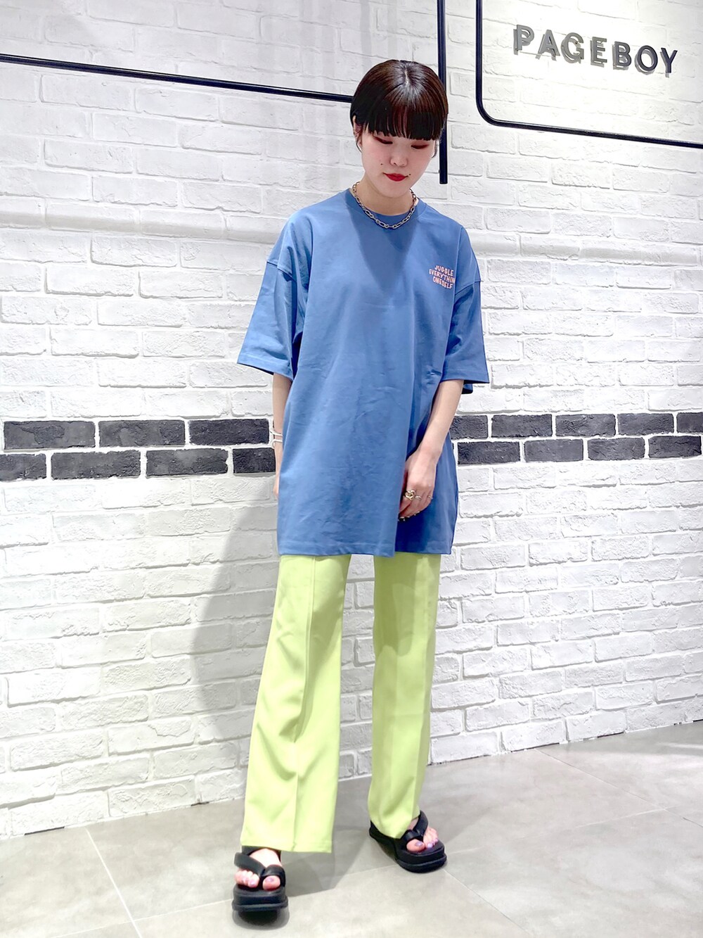 グリーン系のスラックス、ブルー系のTシャツ/カットソー、ブラック系のサンダルを着用したレディースの春コーディネートの2枚目の写真