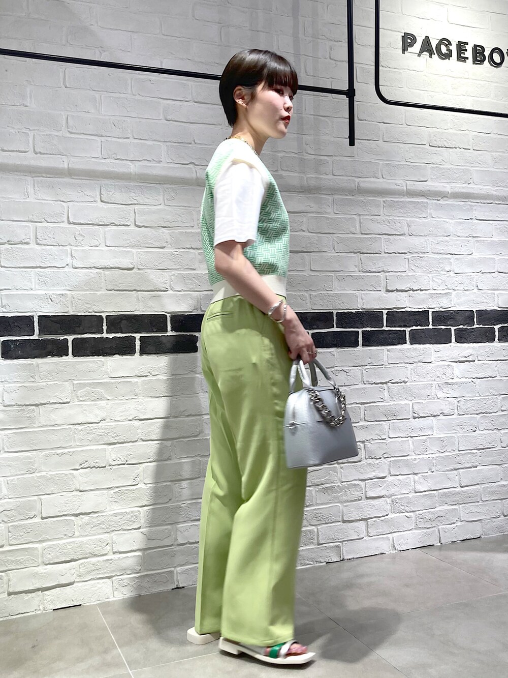 シルバー系のショルダーバッグ、グリーン系のスラックス、シルバー系のサンダルを着用したレディースの春コーディネートの3枚目の写真