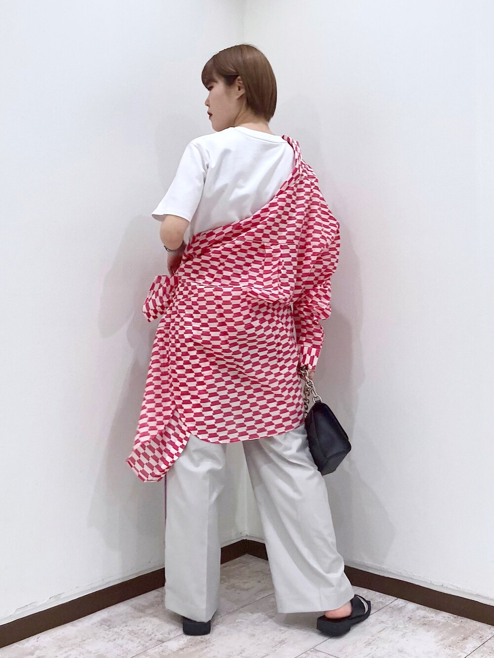 ブラック系のショルダーバッグ、ベージュ系のスラックス、オレンジ系のシャツ/ブラウスを着用したレディースの春コーディネートの5枚目の写真