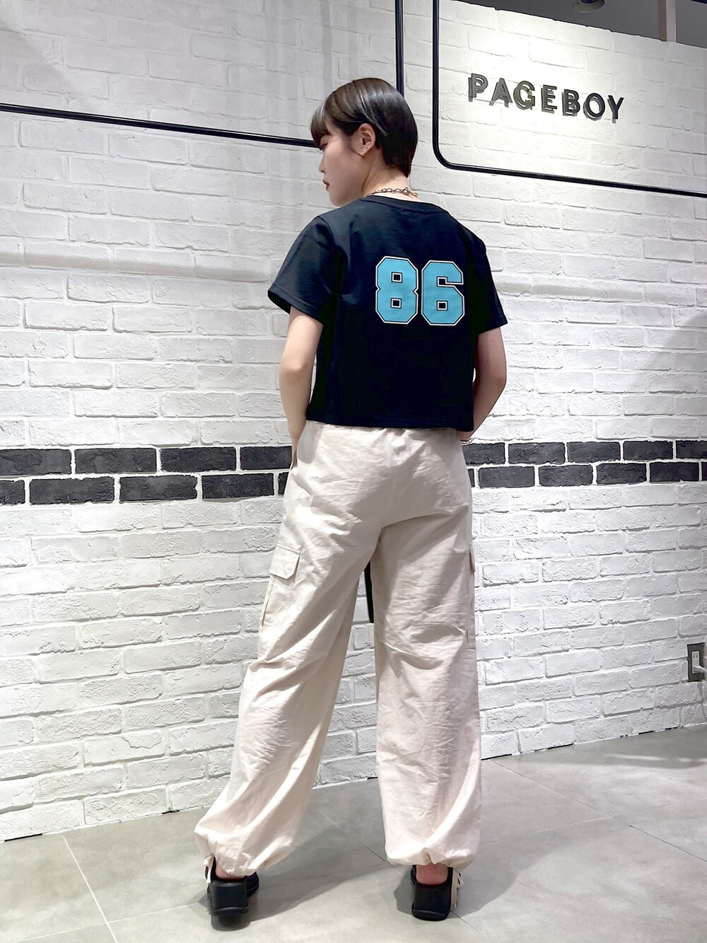 ブラック系のTシャツ/カットソー、ブラック系のショルダーバッグ、ホワイト系のカーゴパンツを着用したレディースの春コーディネートの4枚目の写真