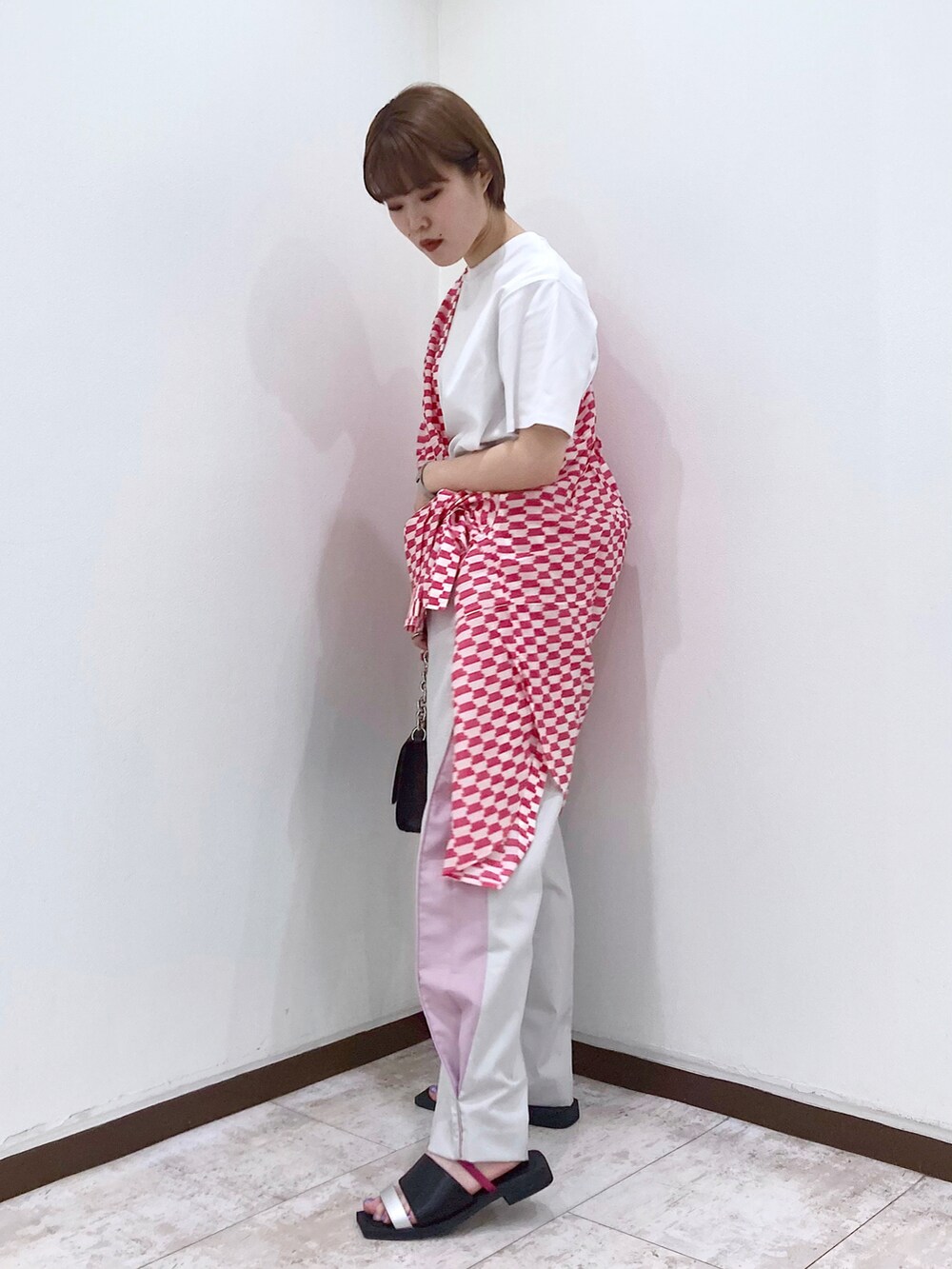 ブラック系のショルダーバッグ、ベージュ系のスラックス、オレンジ系のシャツ/ブラウスを着用したレディースの春コーディネートの3枚目の写真