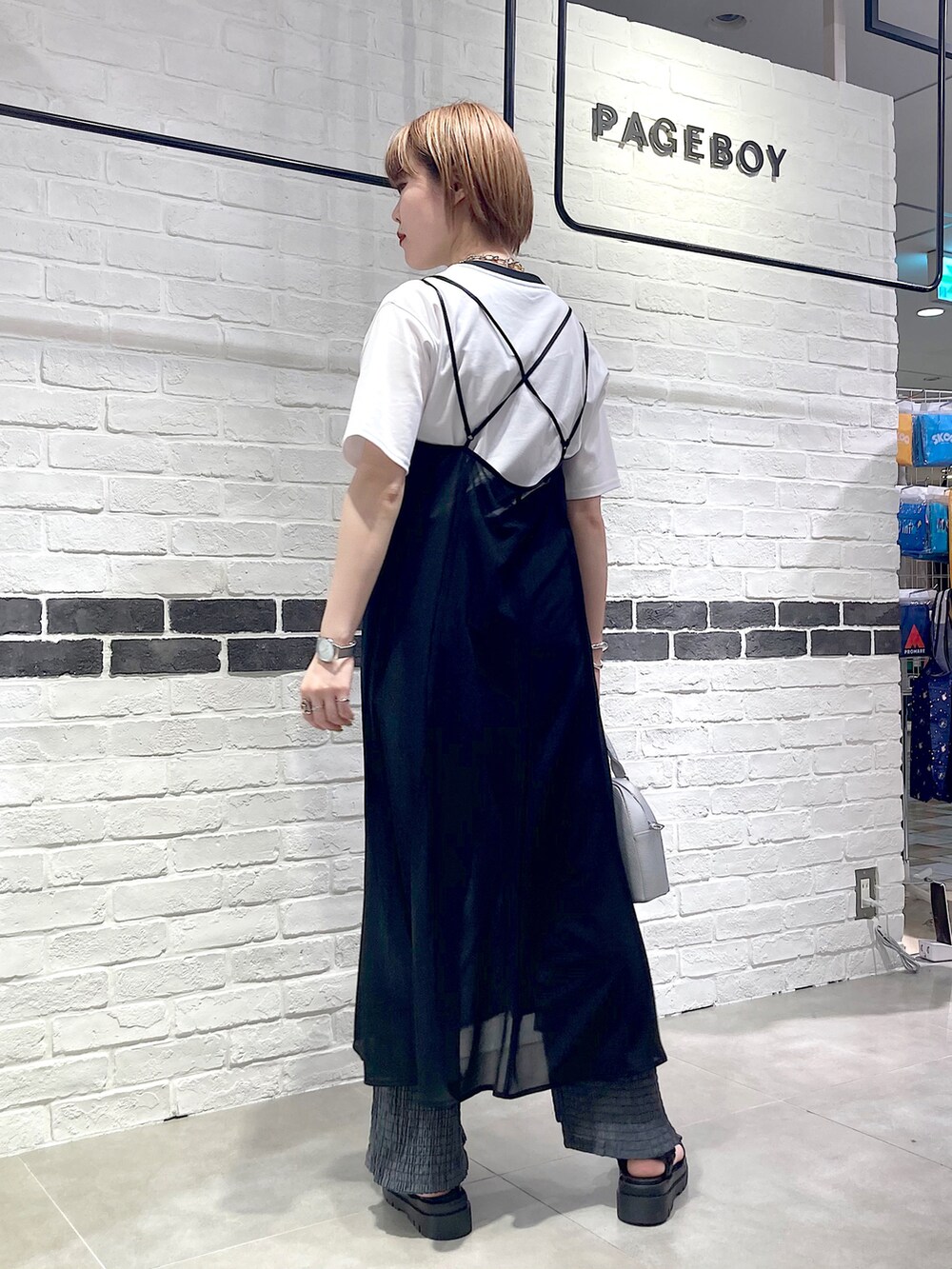 ブラック系のワンピース、ホワイト系のTシャツ/カットソー、シルバー系のショルダーバッグを着用したレディースの春コーディネートの4枚目の写真