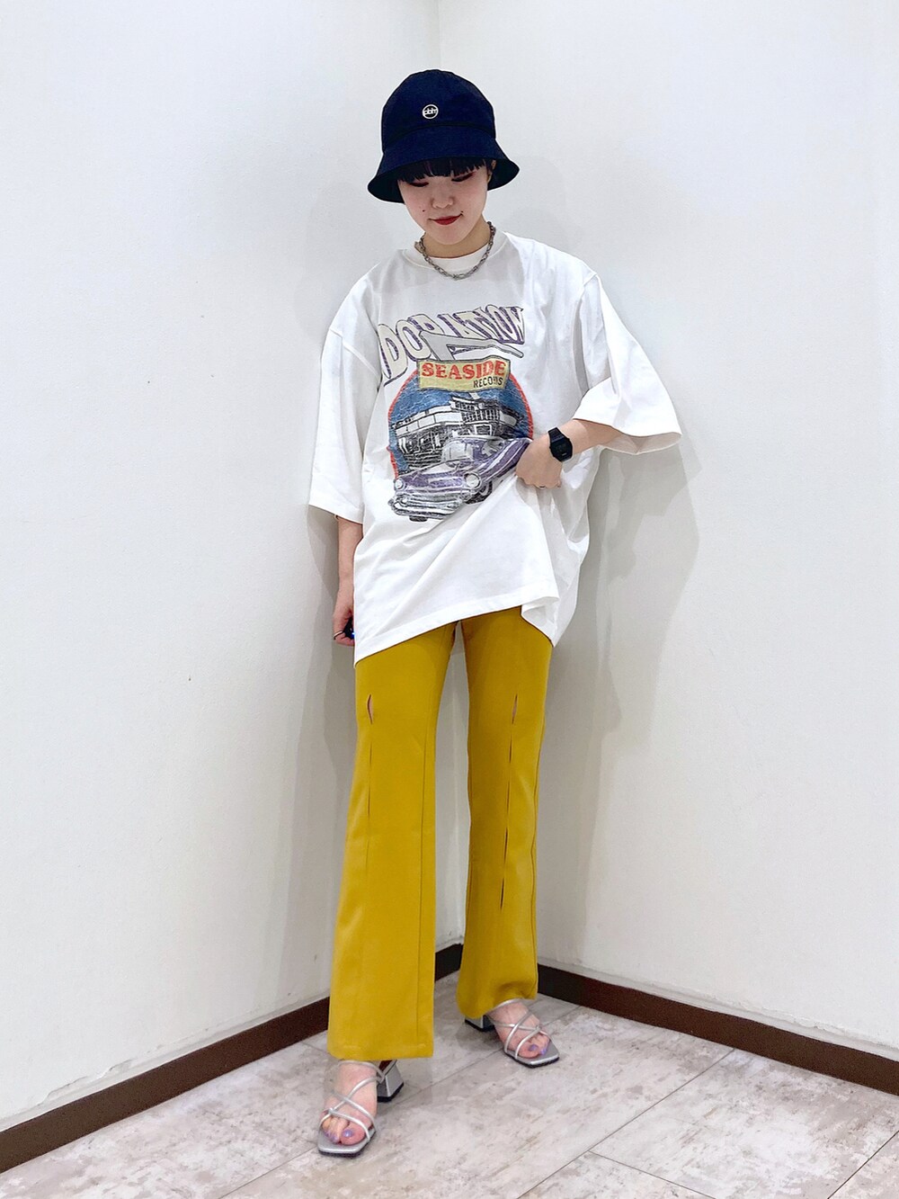 ホワイト系のTシャツ/カットソー、イエロー系のスラックス、シルバー系のサンダルを着用したレディースの夏コーディネートの2枚目の写真