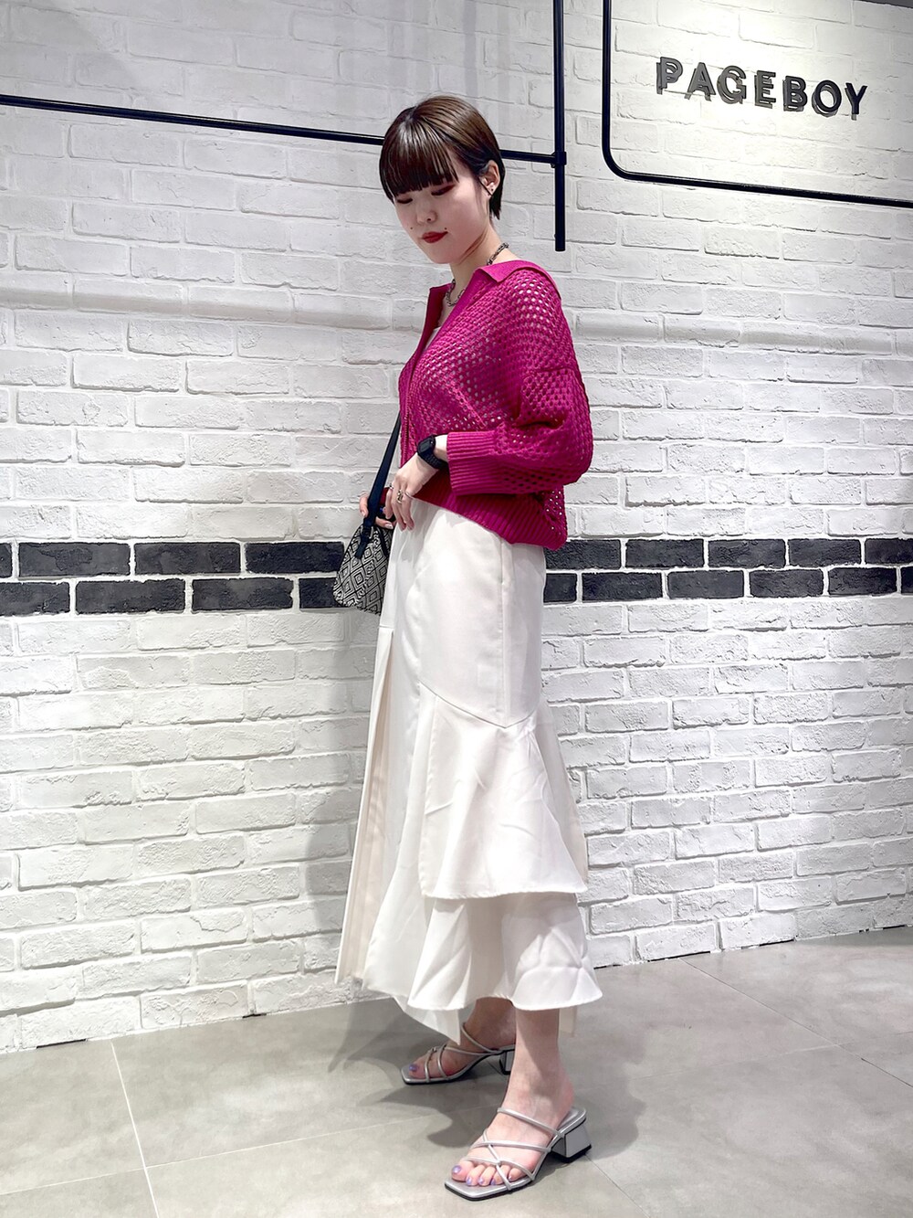 ピンク系のニット/セーター、ブラック系のショルダーバッグ、ホワイト系のタンクトップを着用したレディースの夏コーディネートの3枚目の写真