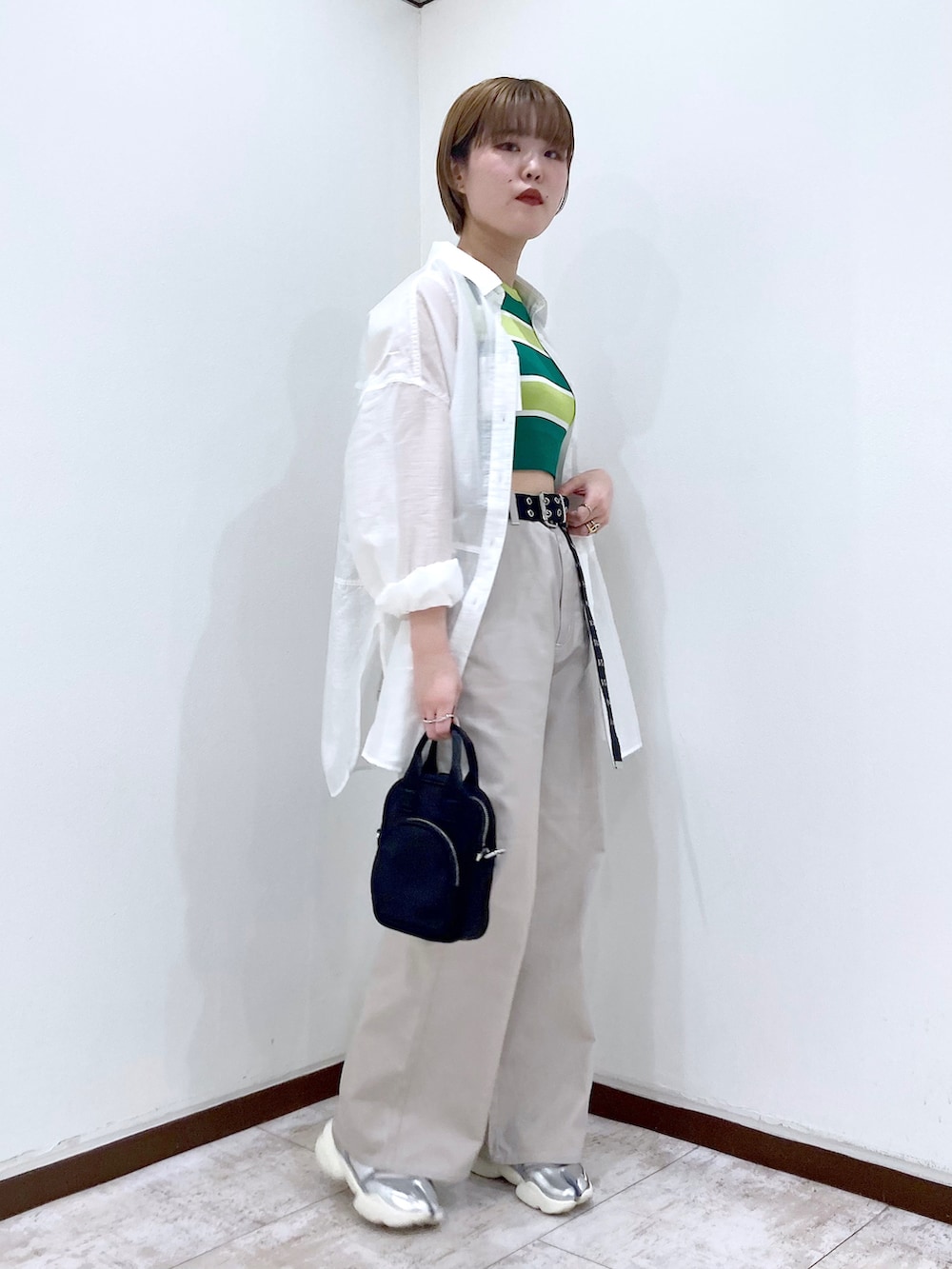 グリーン系のタンクトップ、ホワイト系のシャツ/ブラウス、ブラック系のショルダーバッグを着用したレディースの春コーディネートの2枚目の写真