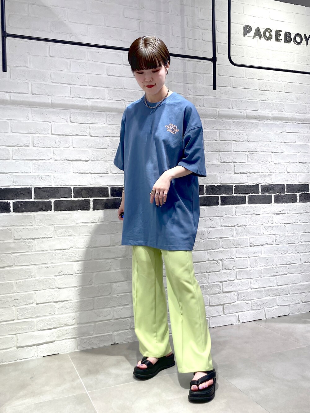 グリーン系のスラックス、ブルー系のTシャツ/カットソー、ブラック系のサンダルを着用したレディースの春コーディネートの3枚目の写真