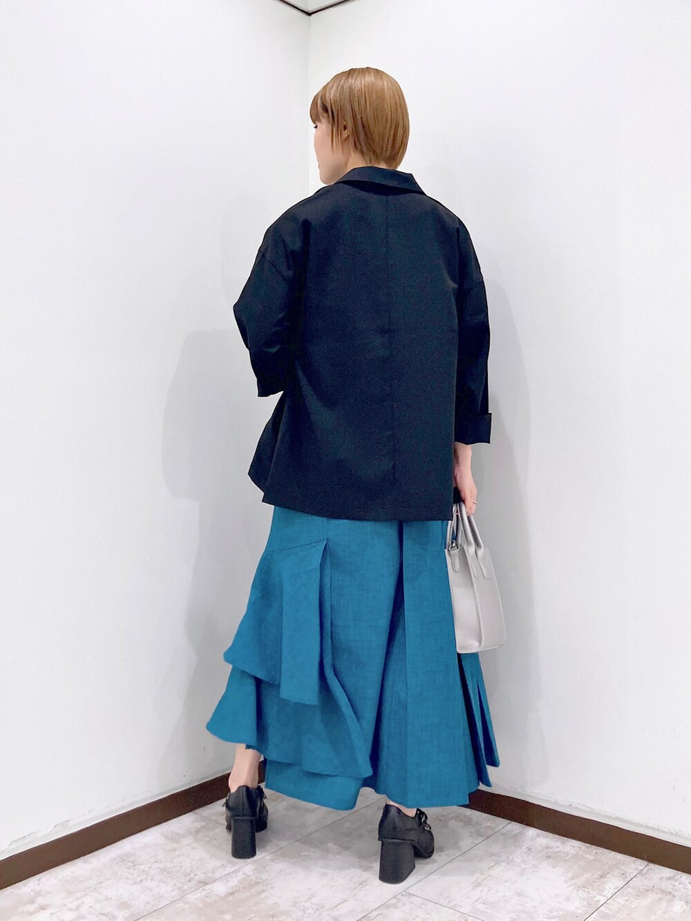 ブラック系のテーラードジャケット、グリーン系のTシャツ/カットソー、シルバー系のショルダーバッグを着用したレディースの春コーディネートの3枚目の写真