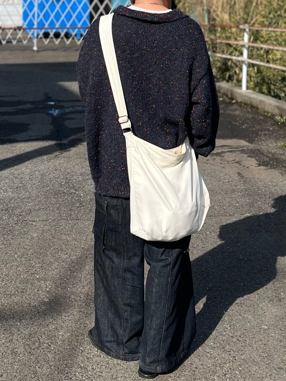 ブルー系のデニムパンツ、ブルー系のニット/セーター、ベージュ系のショルダーバッグを着用したメンズの冬コーディネートの5枚目の写真